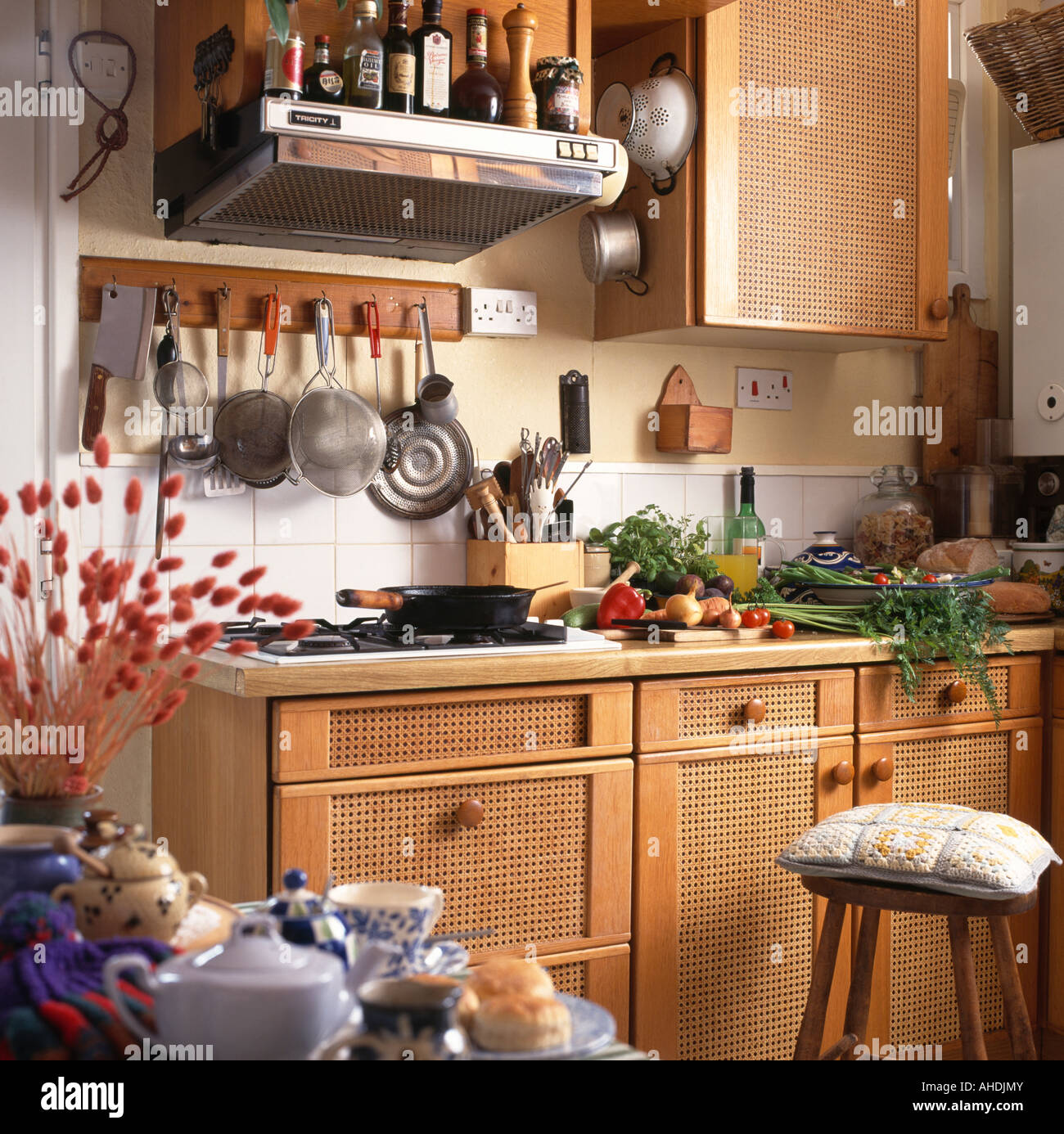 Utensils on rack above built in hob in kitchen with fretwork panels in cupboard doors