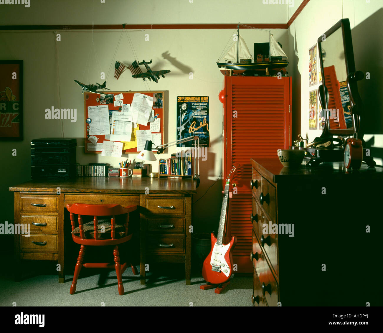 nineties study with old wooden desk and guitar leaning against red cupboard Stock Photo