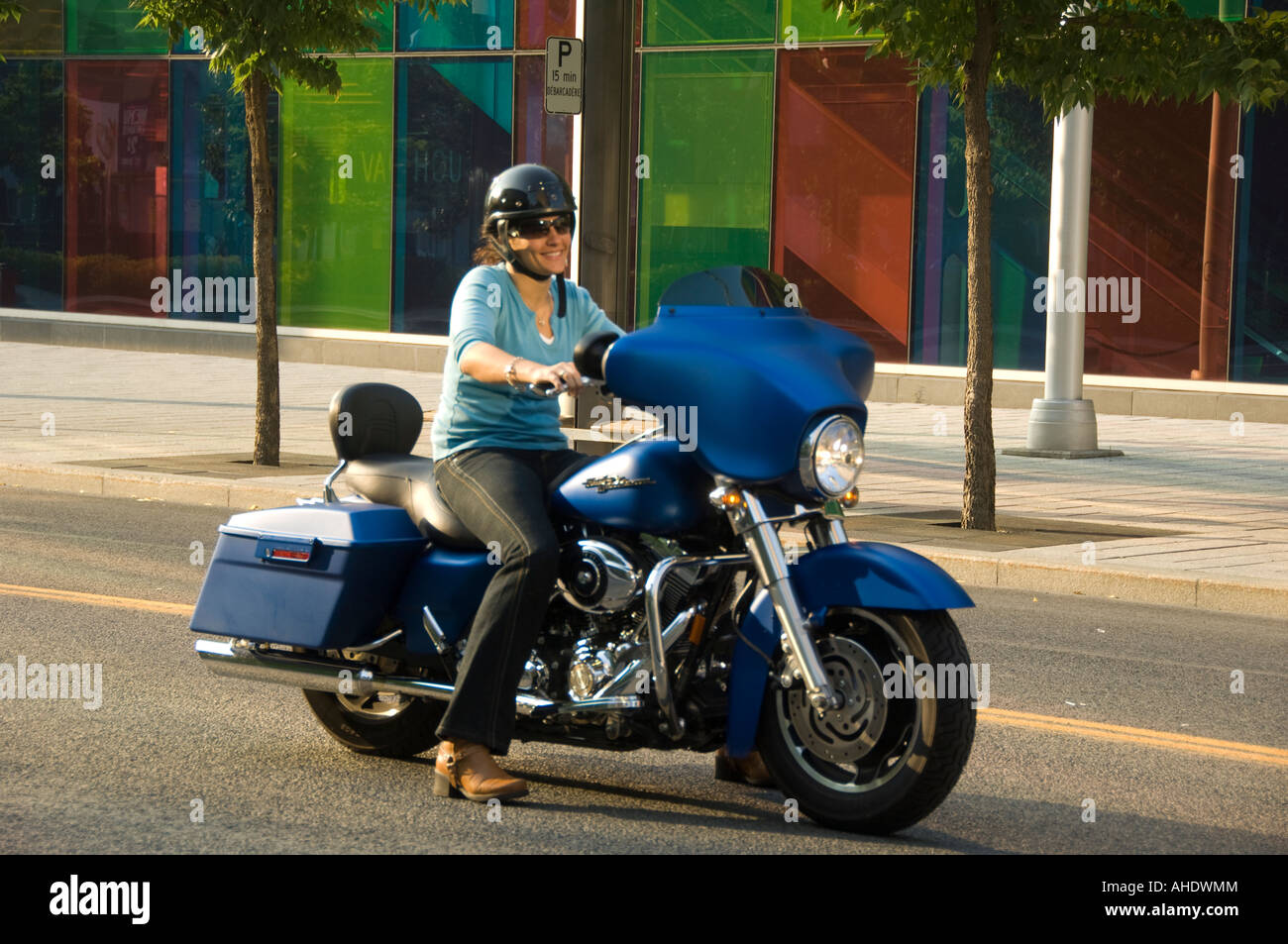 Canada Montreal Quebec Woman on motorcycle riding past the colorful Montreal Convention Center Stock Photo