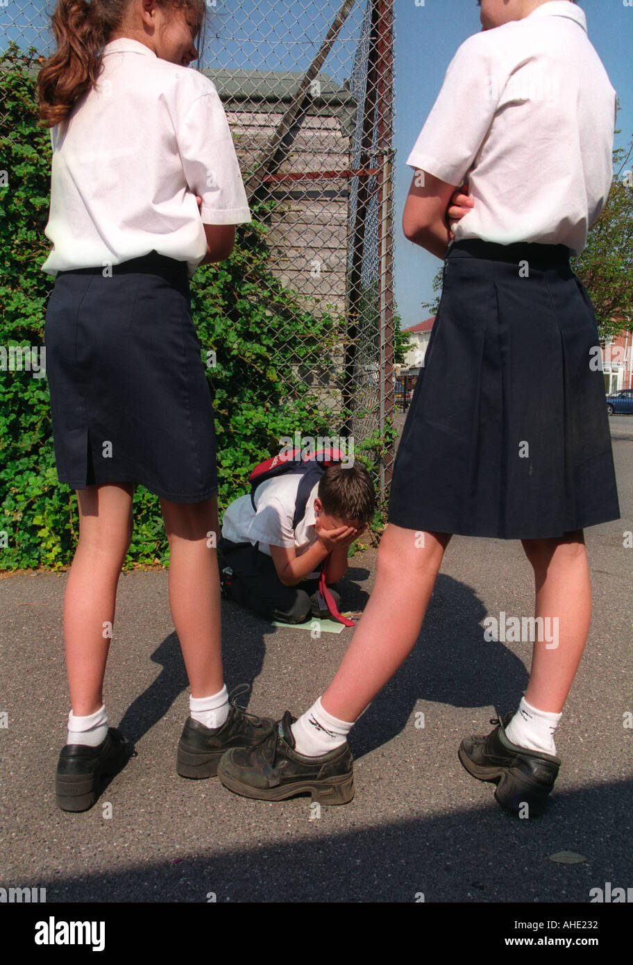 Girls bullying smaller boy at school modelled. Stock Photo
