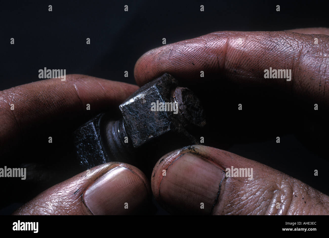 Old nut and bolt in dirty oily fingers Stock Photo