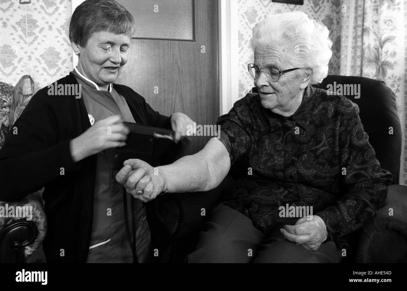 A district nurse measures a patient's blood pressure during a home visit, London, UK. Stock Photo