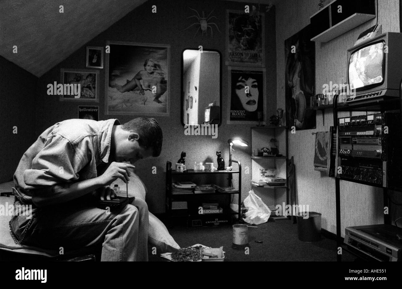 A young man tries to repair his personal stereo in his bedroom, hostel for single homeless persons, Lincolnshire, UK. Stock Photo