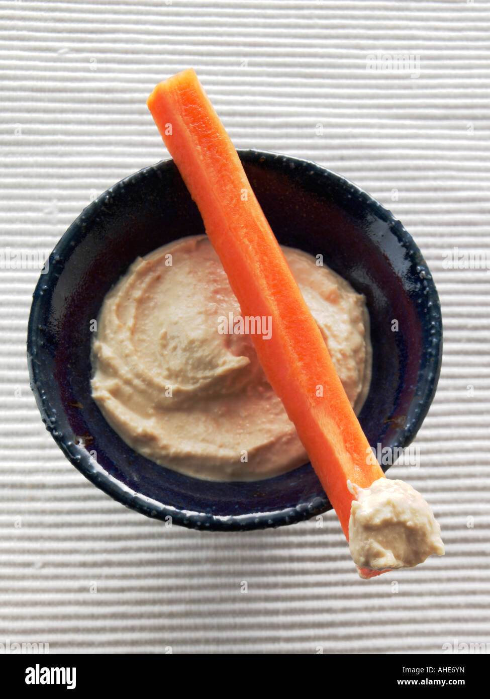 A bowl of houmous with a carrot stick editorial food Stock Photo