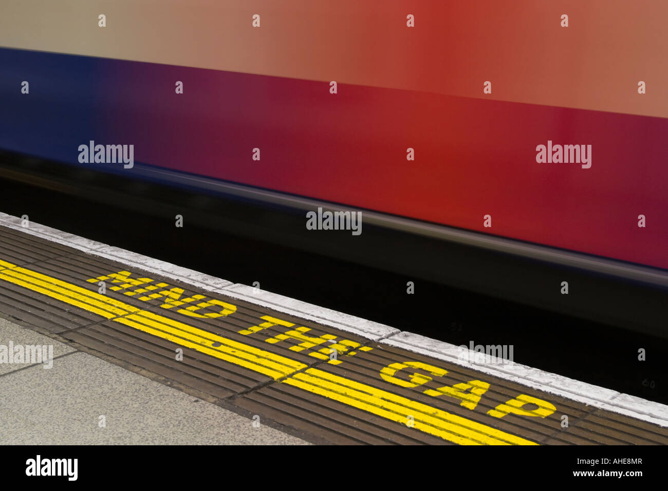 Mind The Gap sign with London Underground tube going past at Waterloo
