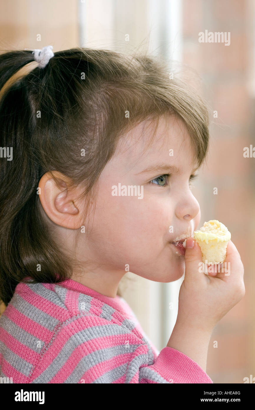 3 4 yearl girl taking a bite of cake Stock Photo