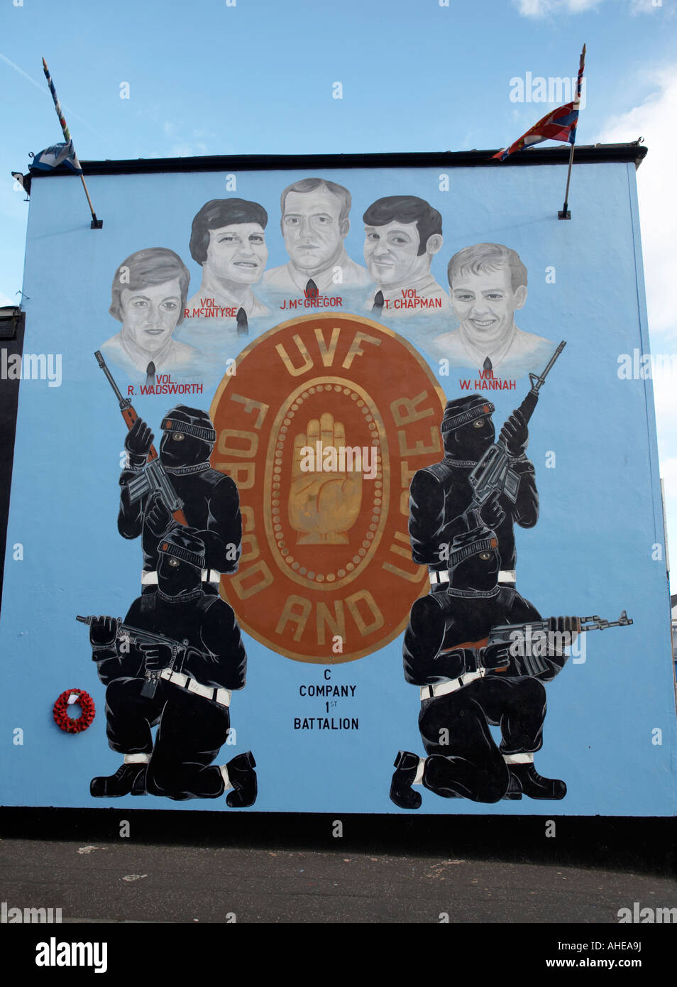 UVF Ulster Volunteer Force memorial mural to dead loyalist terrorists featuring UVF logo and masked armed terrorists Stock Photo