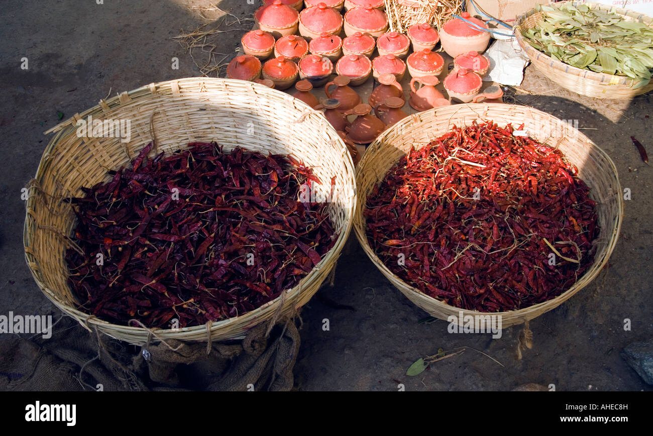 Two baskets of dried hot red chillies for sale in the open air market Thimpu Bhutan Earthenware pots and dried bay leaves in bac Stock Photo