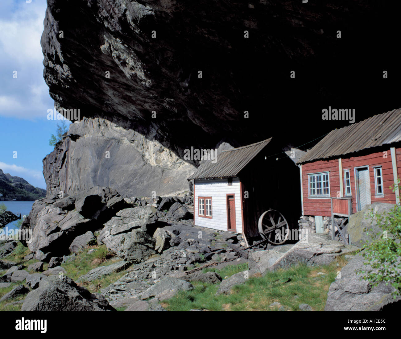 Picturesque old timber houses beneath 'Helleren' (a huge rock overhang), Jøssingfjord, Rogaland, Norway. Stock Photo