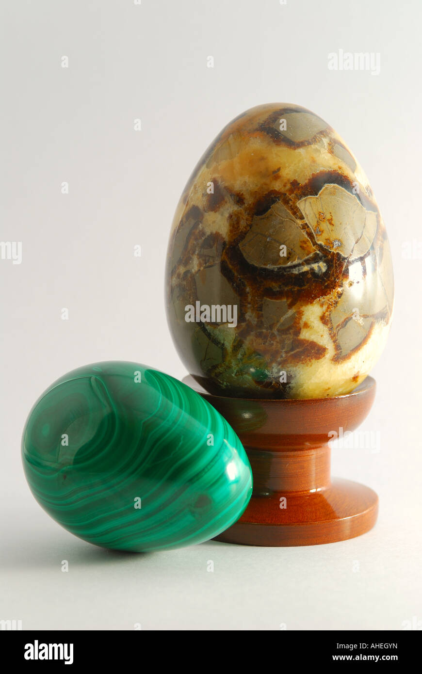 Stone eggs two carved stone eggs, one sitting on a turned wooden