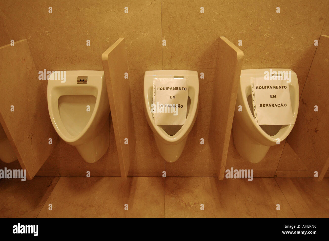 Row of three white ceramic urinals in men toilet room with "out of