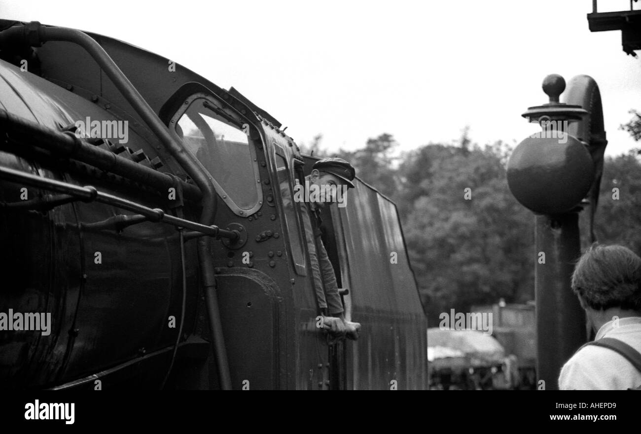 Steam engine driver looking out of cab of locomotive on preserved railway line at Goathland in north Yorkshire Stock Photo