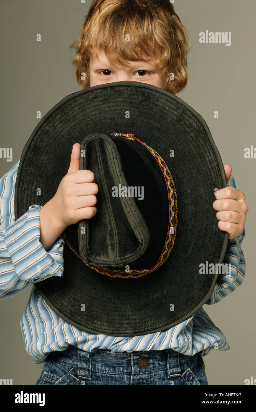 Young boy hiding part of face with large cowboy hat Stock Photo