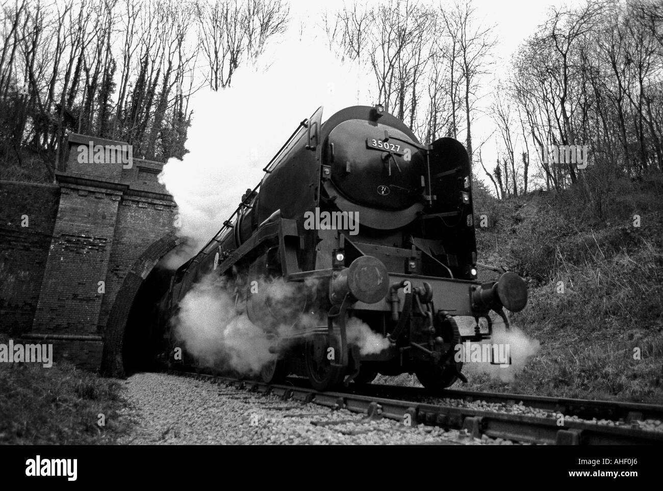 British Railways Merchant Navy class steam locomotive bursts out of Sharpthorne Tunnel on the Bluebell Railway. Stock Photo
