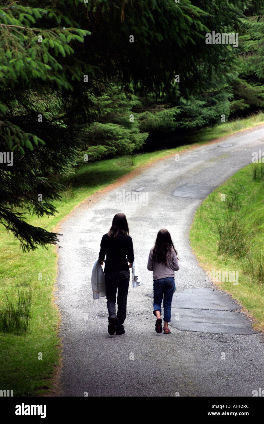 rear view of two young girls walking down a quiet country lane Stock Photo