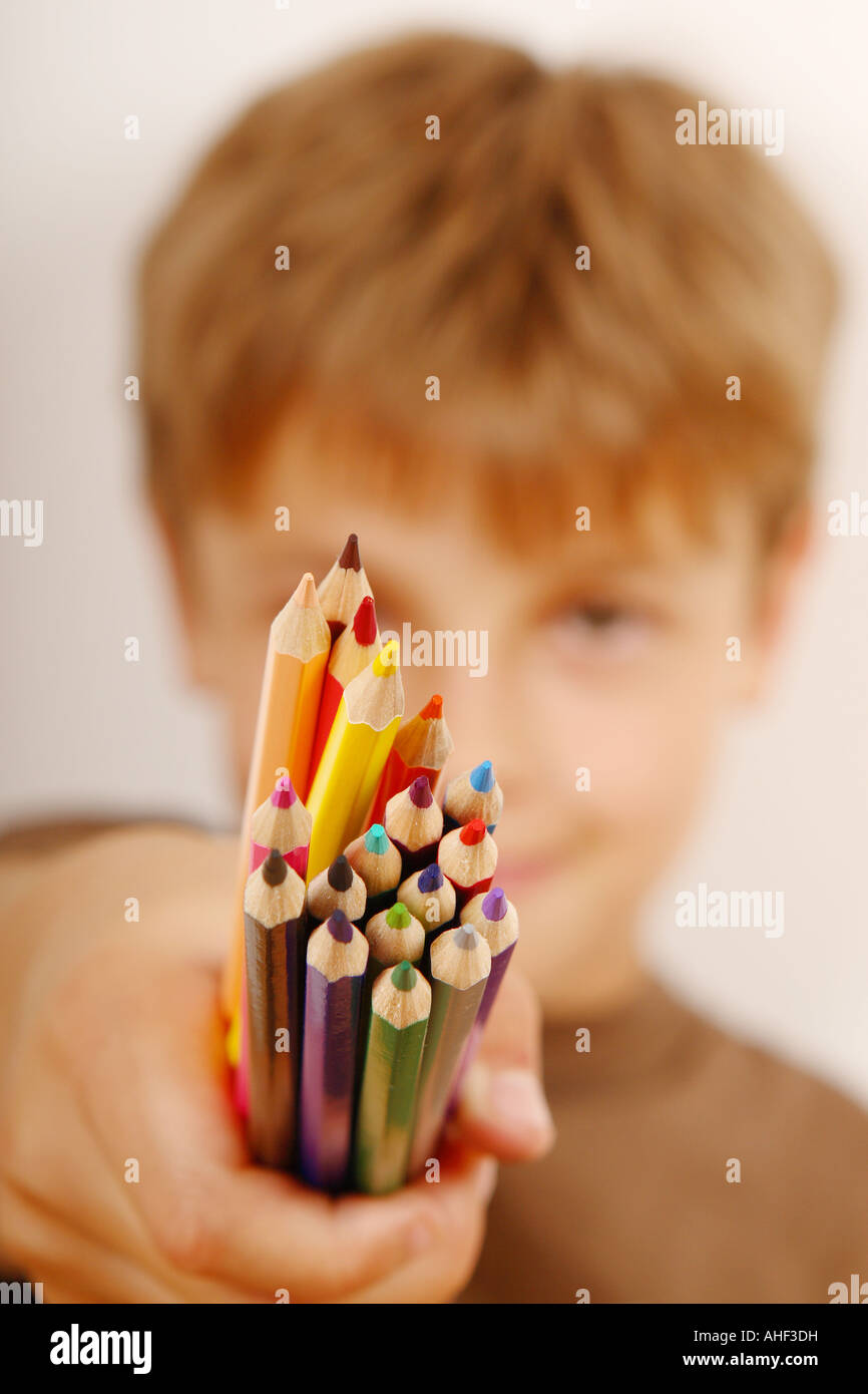 Young boy holding a bunch of colour crayon pencils Stock Photo