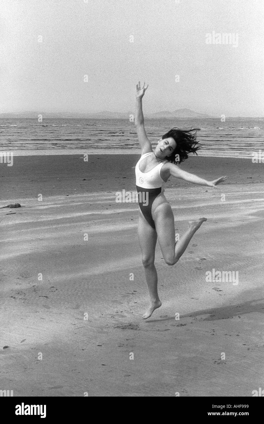 Girl in a One Piece Bathing Suit Dancing Along the Beach Stock Photo