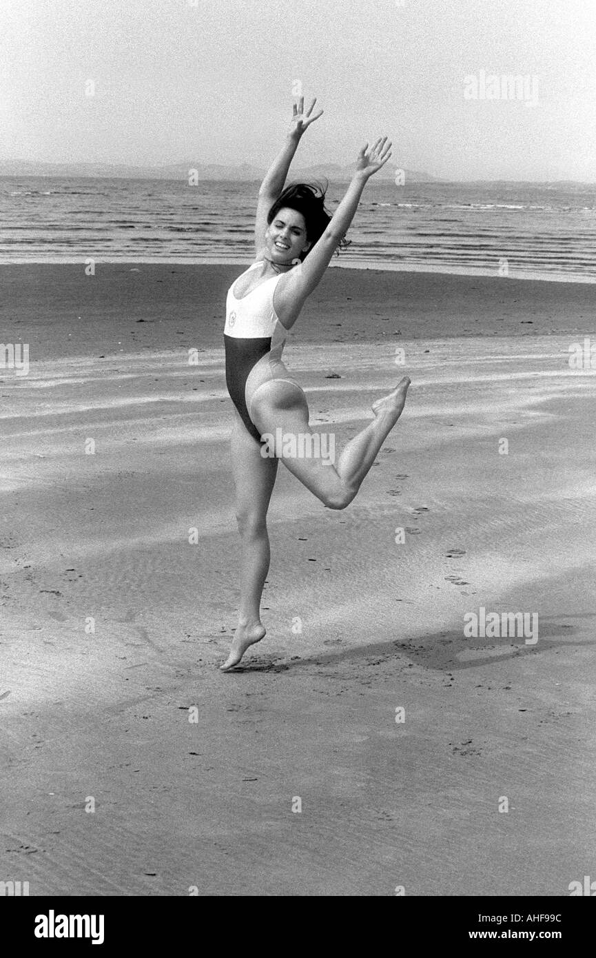 Girl in a One Piece Bathing Suit Dancing Along the Beach Stock Photo
