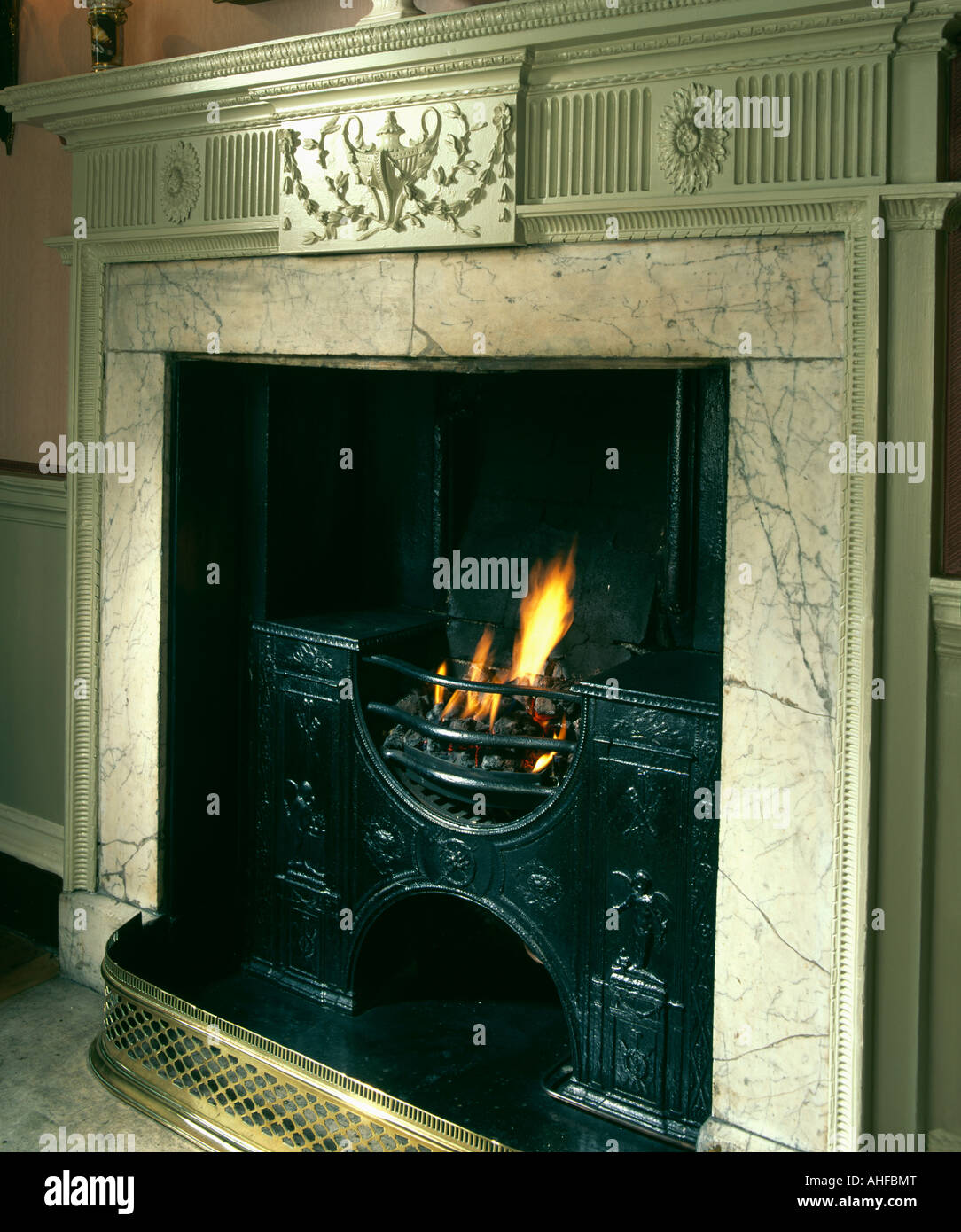 Close Up Of Marble Fireplace With Lighted Fire In Cast Iron Grate