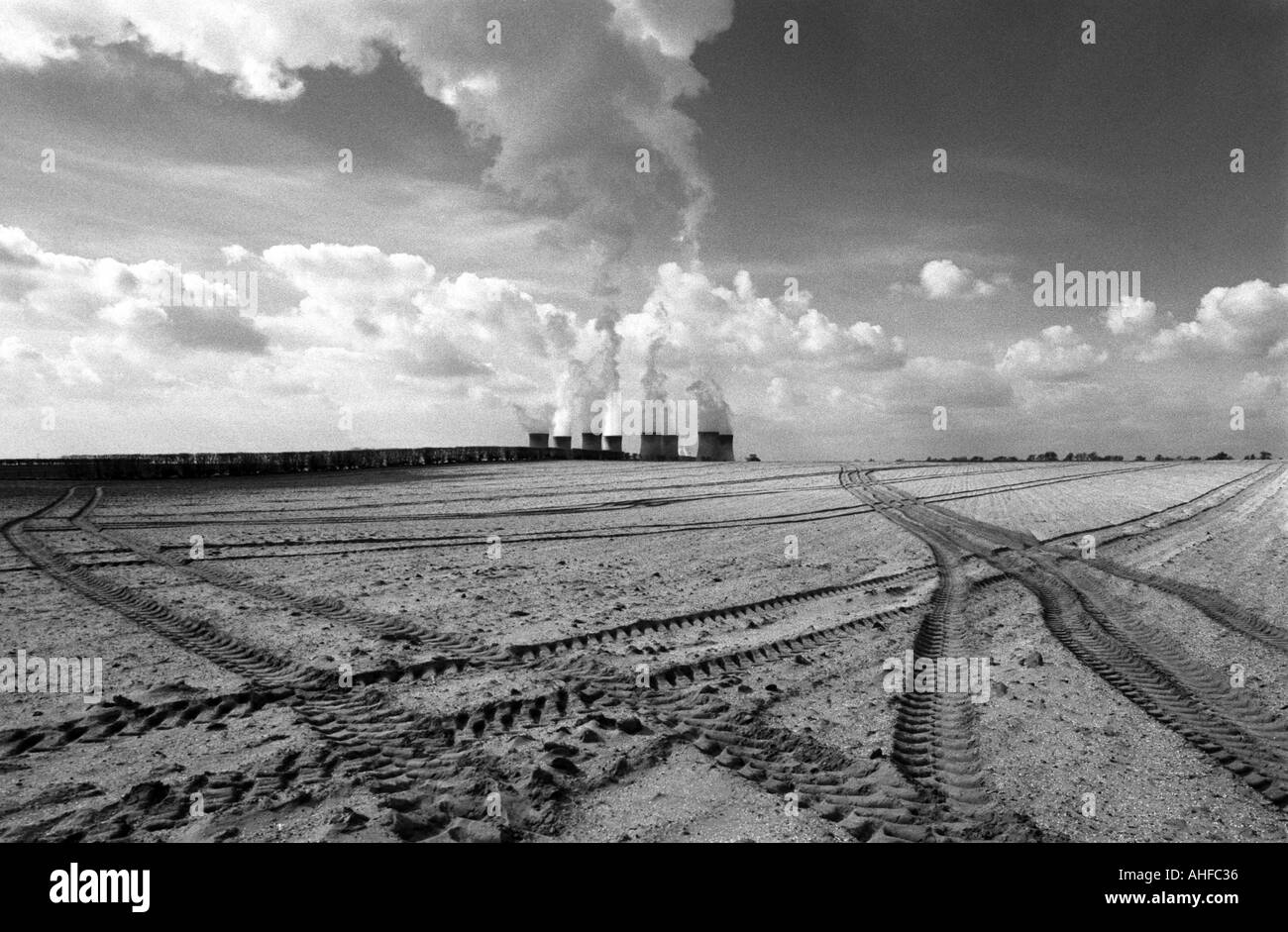 Smoke from the chimneys of a power station close to an empty agricultural field with tractor tracks, Lincolnshire, UK. Stock Photo