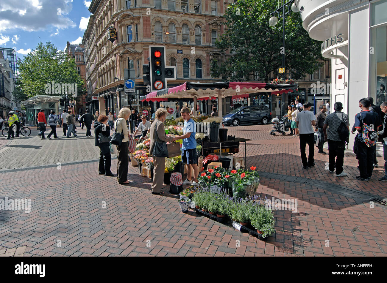 Busy summer street scene showing street trader in pedestrian area. New