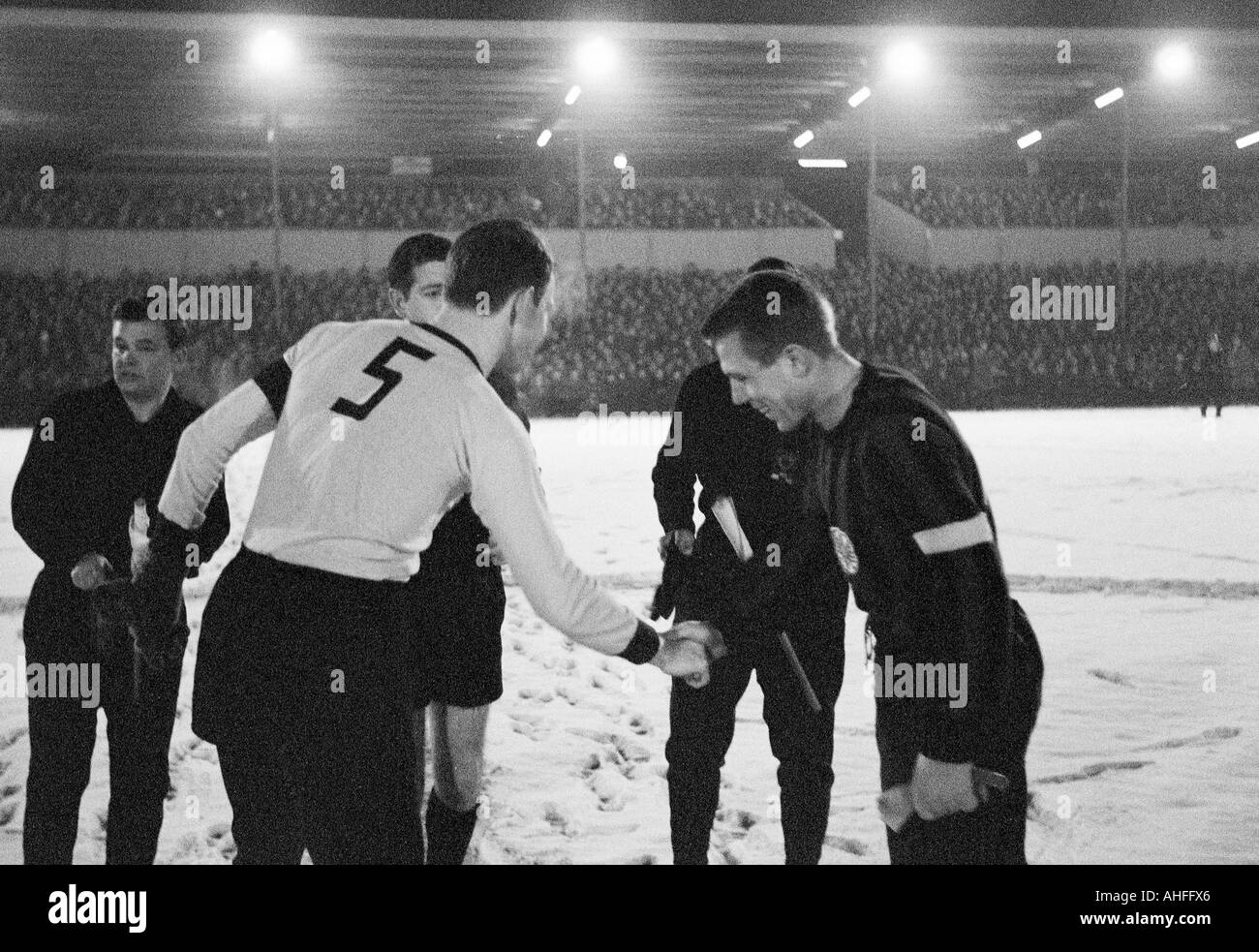 football, Bundesliga, 1965/1966, Rote Erde Stadium in Dortmund, Borussia Dortmund versus Eintracht Frankfurt 3:0, game on snow ground, referee Alfred Ott (covered) and assistants, team captains Wolfgang Paul (Dortmund) left and Dieter Lindner (Frankfurt) Stock Photo