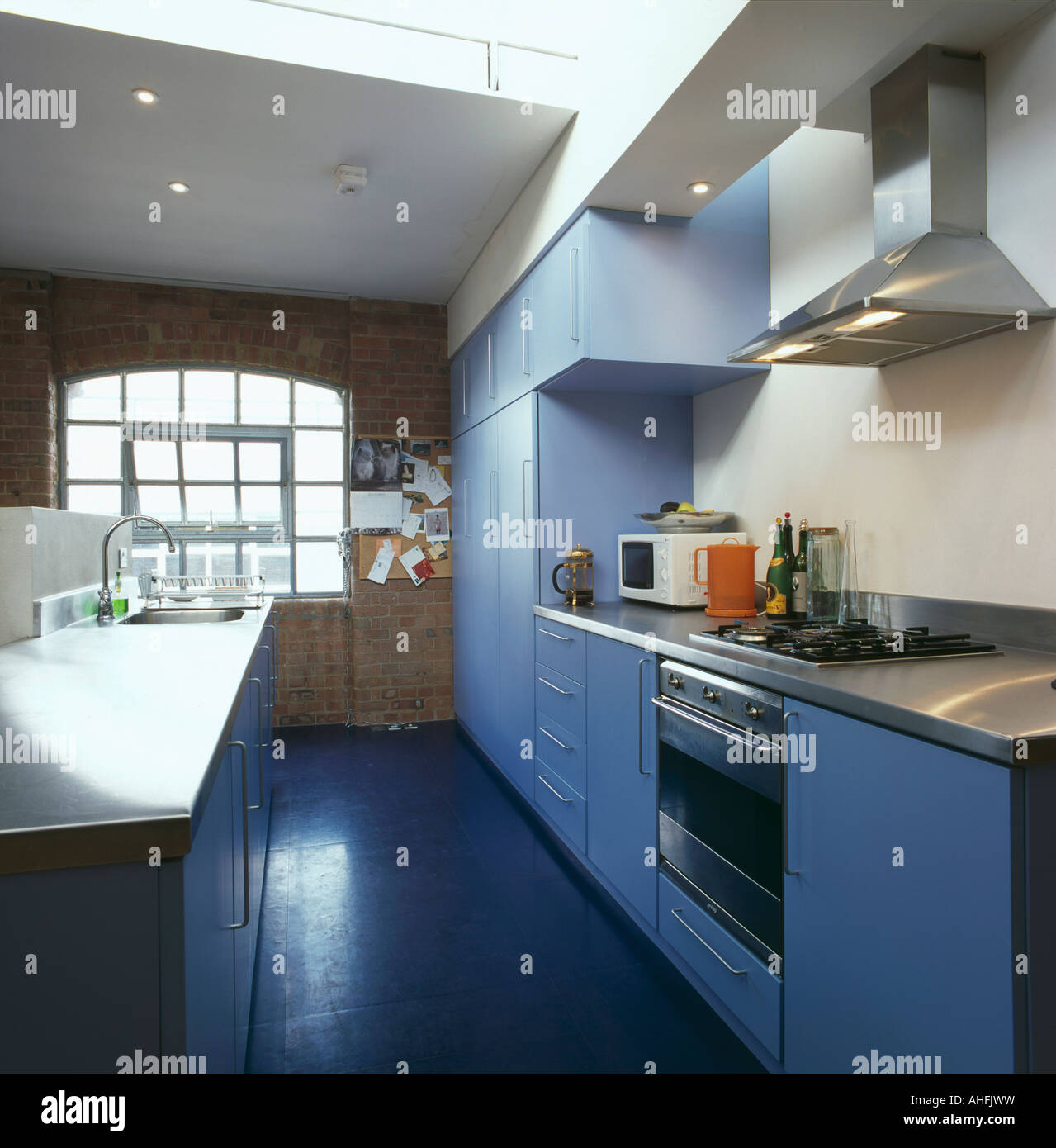 Blue units and painted floorboards in loft conversion kitchen Stock
