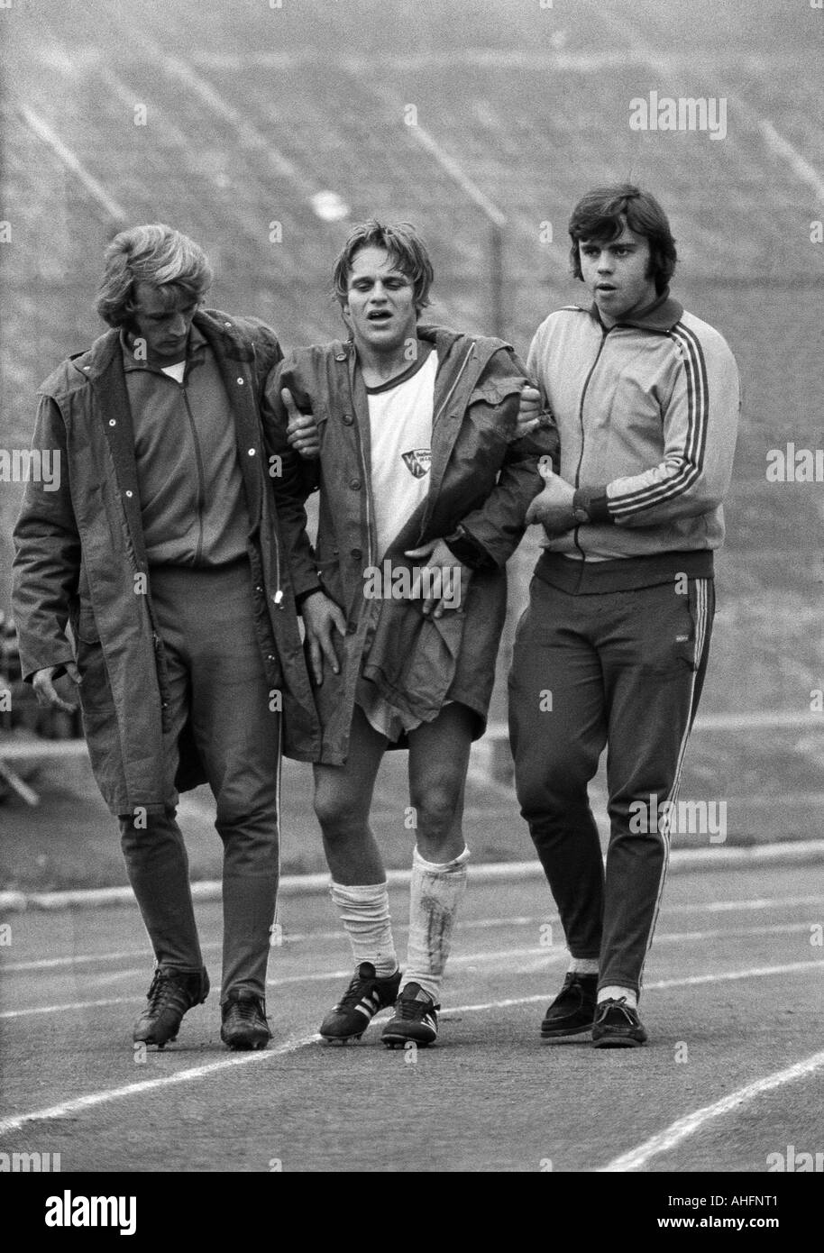 football, Bundesliga, 1972/1973, Stadium am Zoo in Wuppertal, Wuppertaler SV versus VfL Bochum 3:0, injured football player, guardians led Hans Guenther Etterich (Bochum) from the pitch Stock Photo