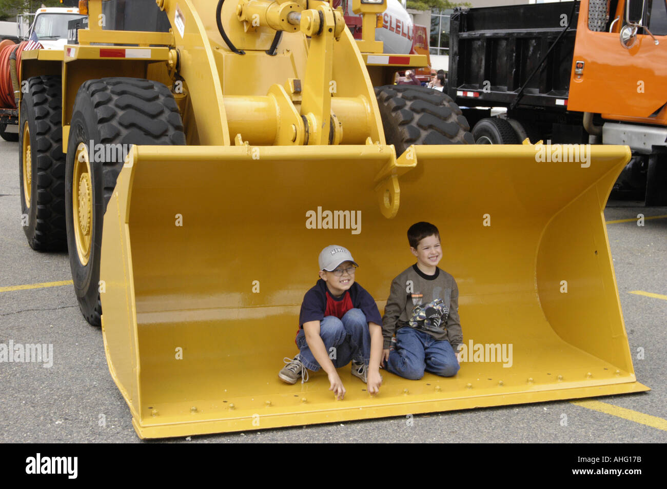 Two kids in large bucket of front loader Stock Photo Alamy