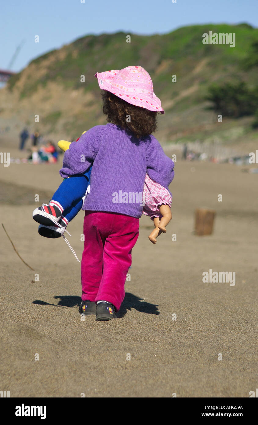Little girl at beach carrying dolls Stock Photo Alamy