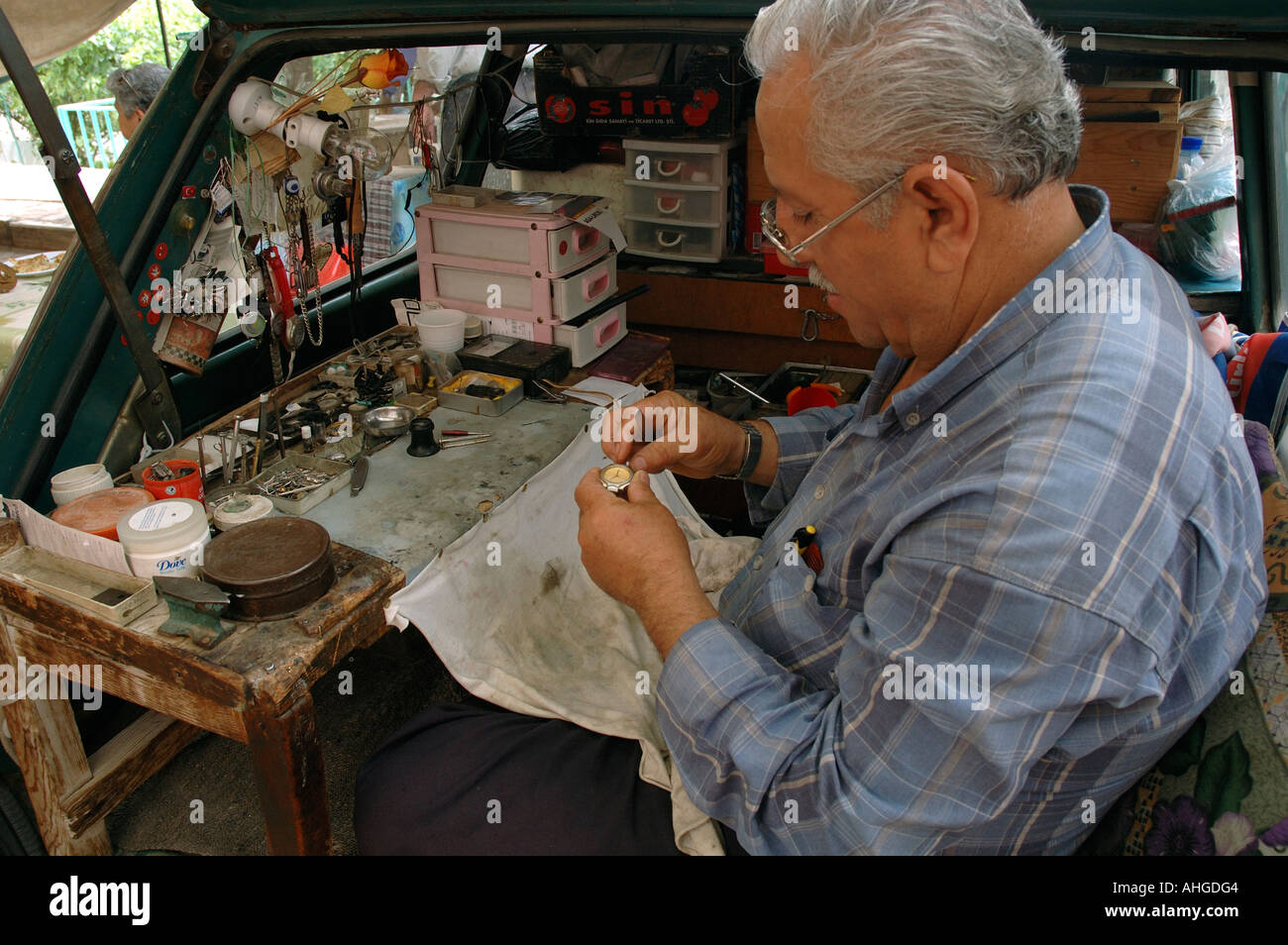 Man fixing and repairing watches from the back of his car in Kalkan a Southern Turkish town. Stock Photo