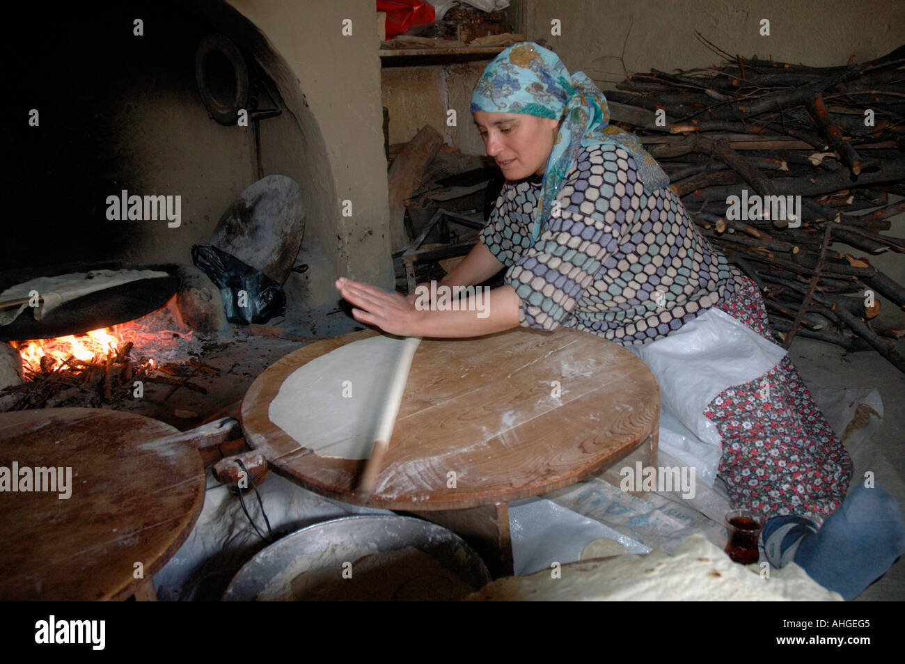 Woman making rural Turkish flat bread in open oven at home in small