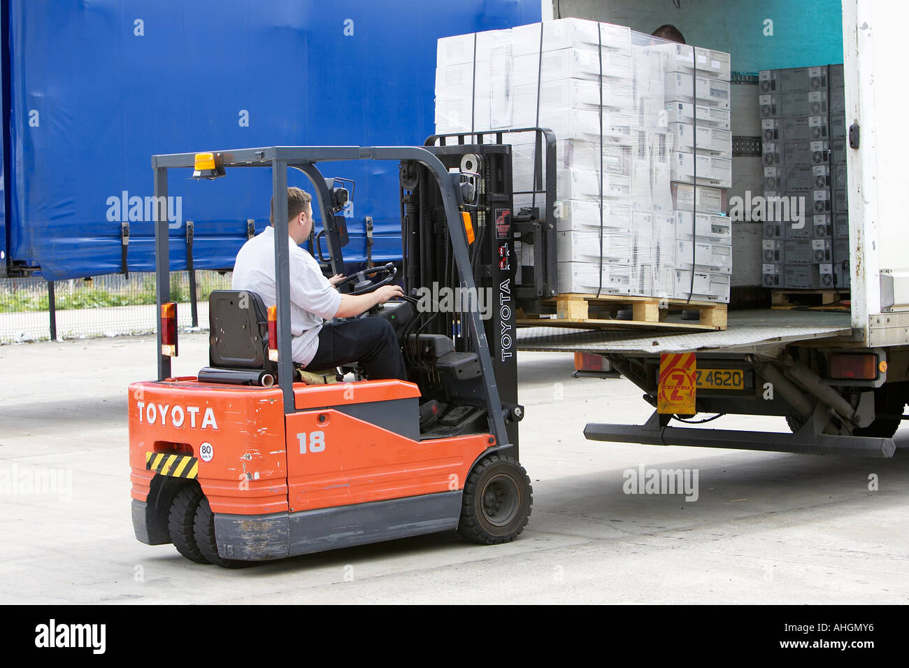 workmen unloading tail lift lorry with forklift containing pallet ...