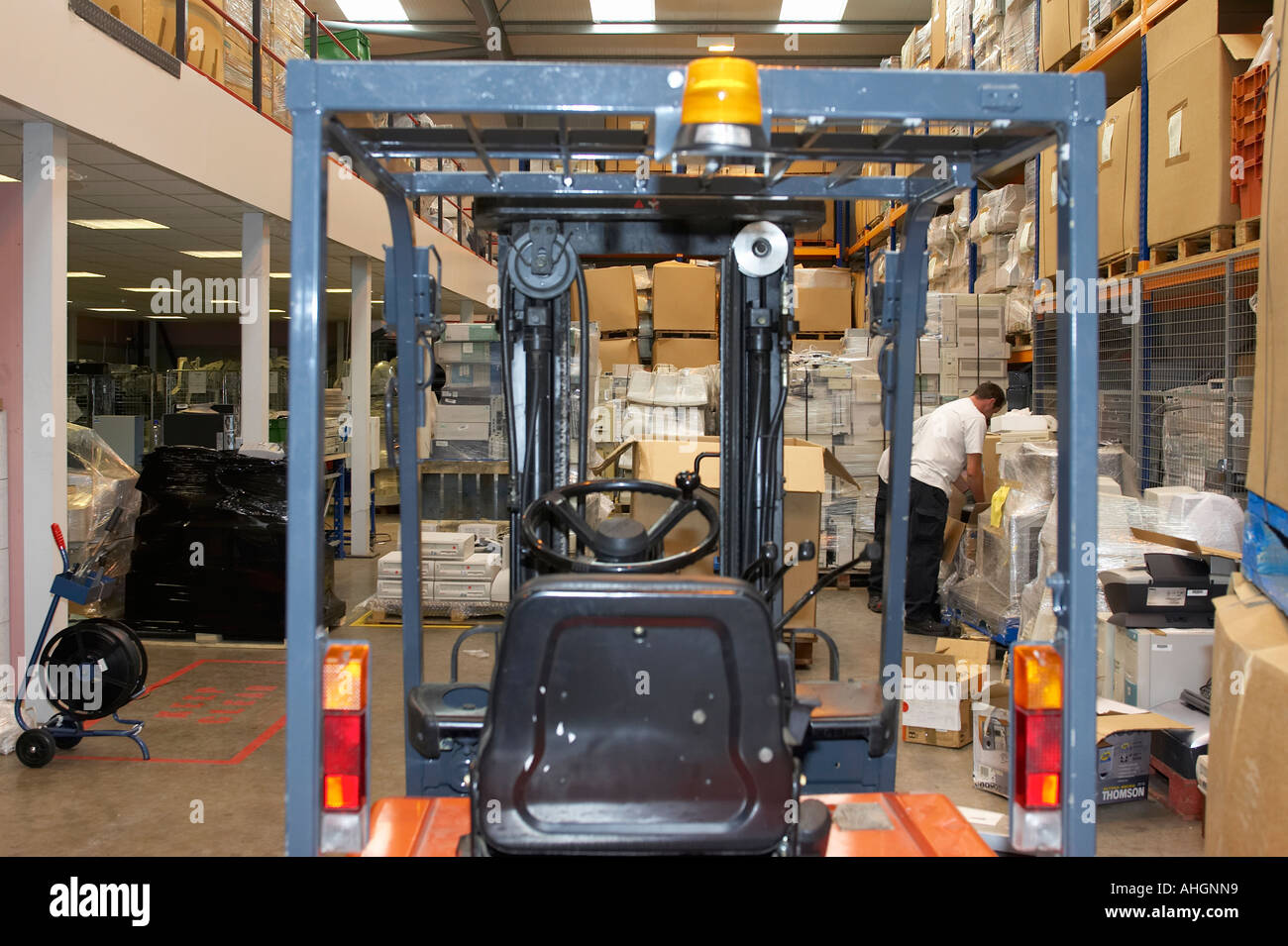 forklift truck and workers in warehouse full of piles of pallet wrapped ...