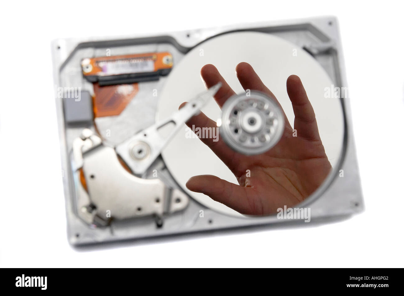 hand reflected in disc of open broken hard drive against white ...
