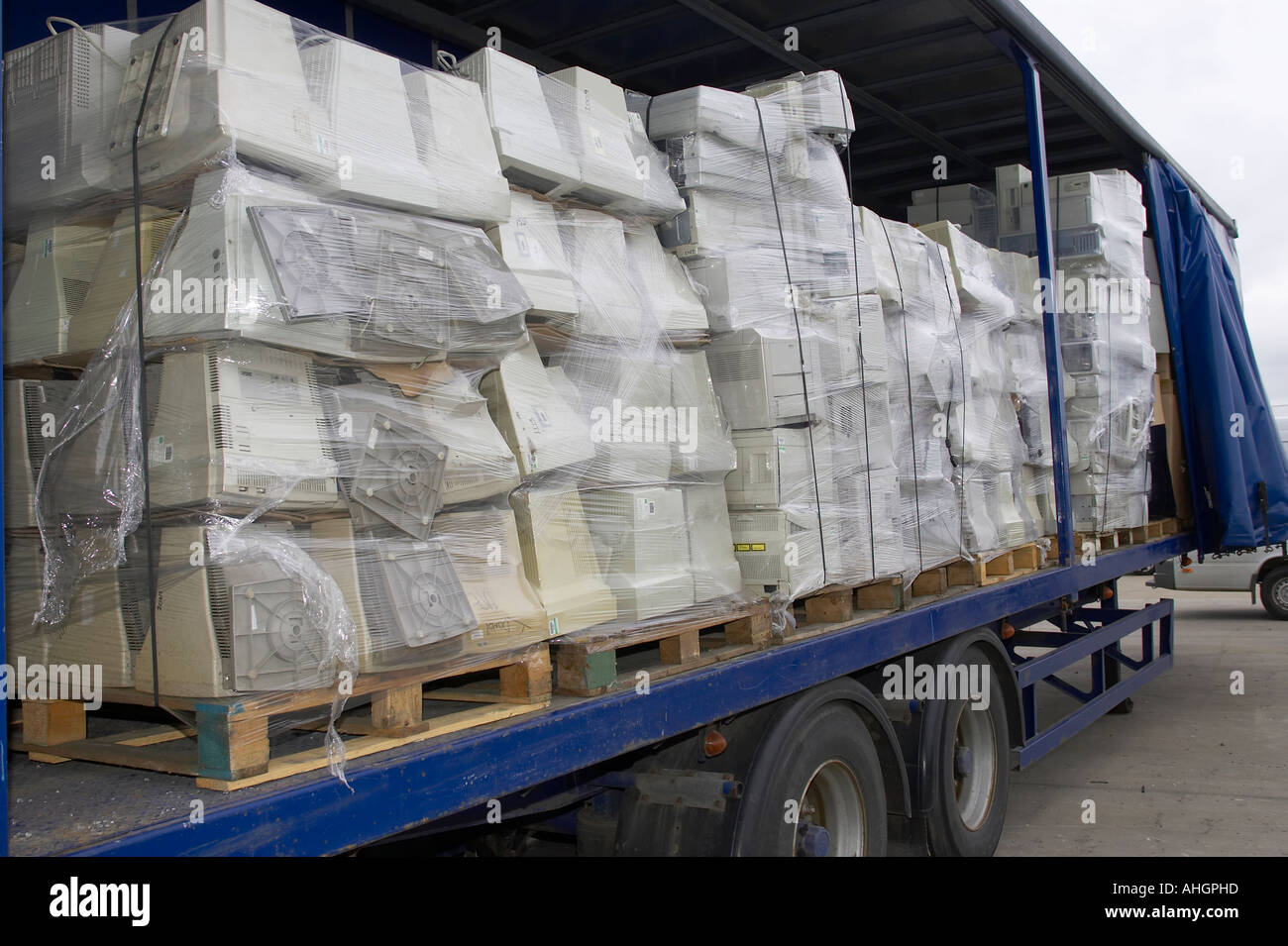 Open side of blue curtain lorry trailer containing pallets of wrapped computer monitors and system boxes for recycling Stock Photo