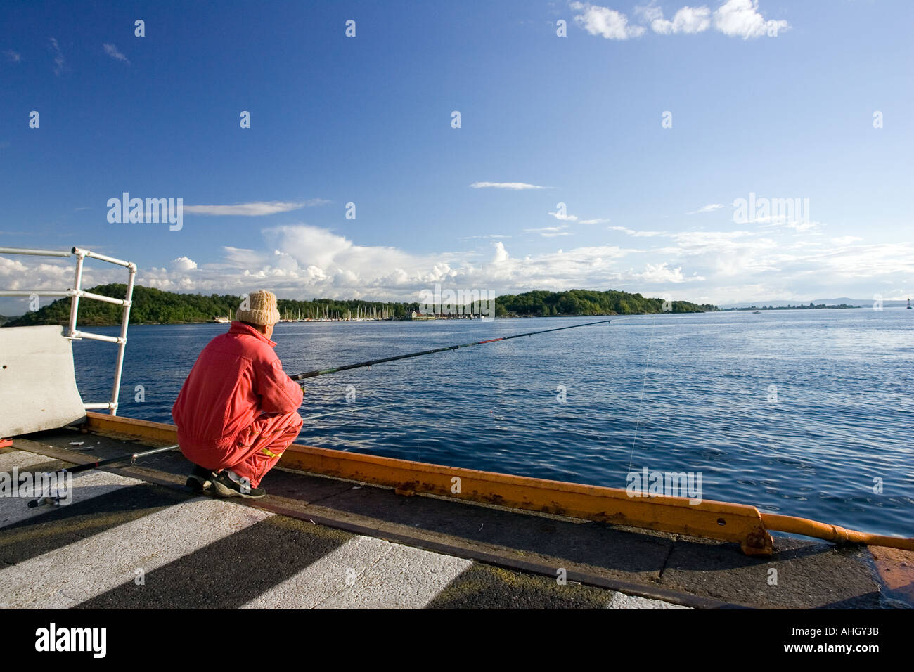 Calming image of a man in red fishing on a blue environment. Stock Photo