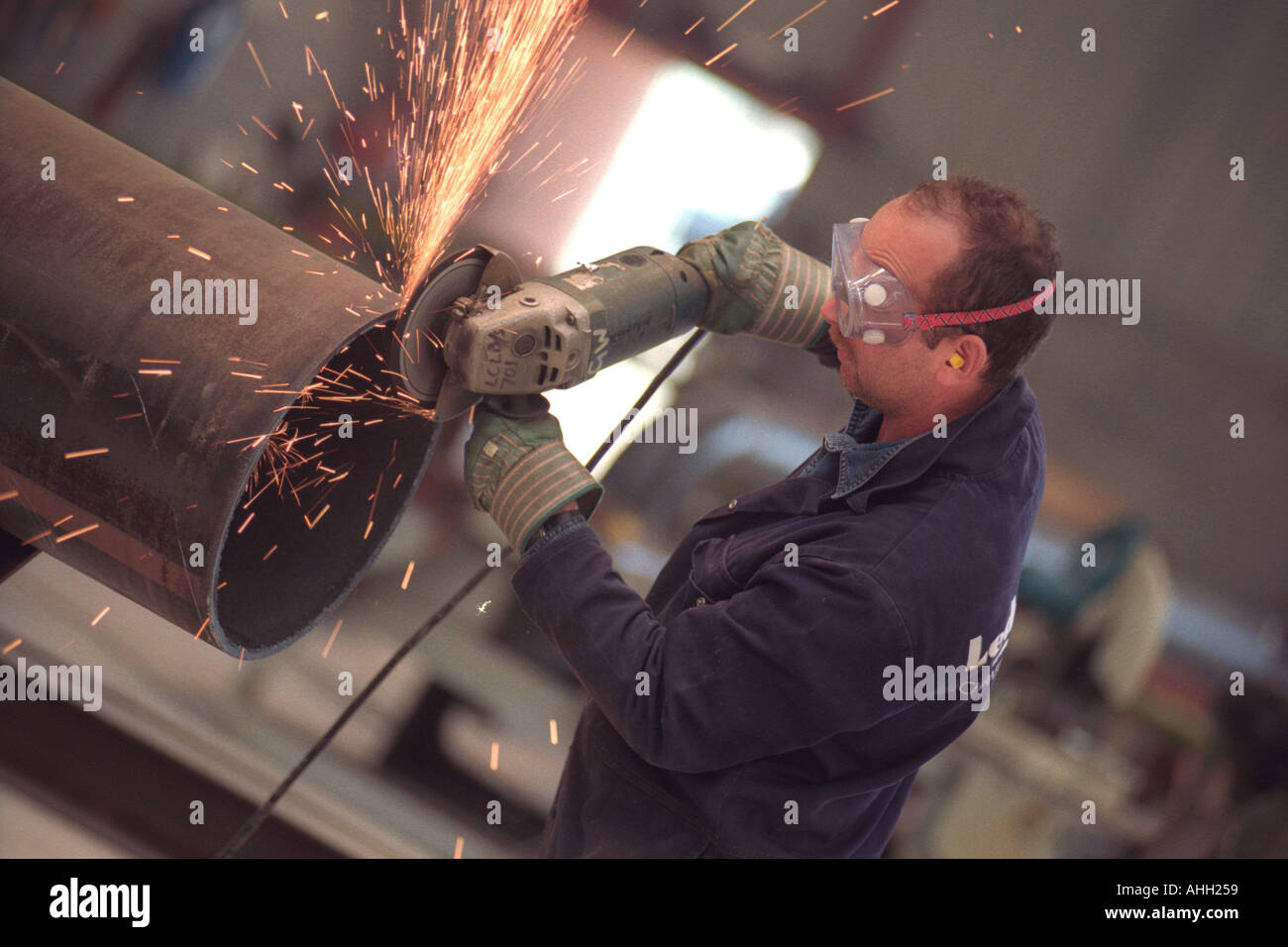 Grinder working on a pipe for the oil industry Milford Haven Pembrokeshire West Wales UK Stock Photo