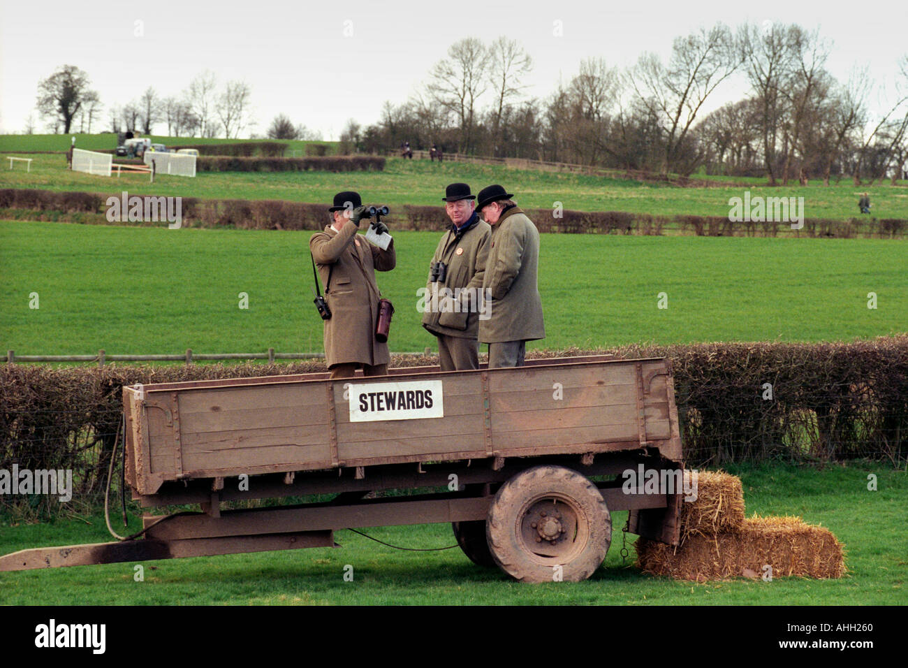 Horse racing stewards stand in a farm trailer to watch the racing at