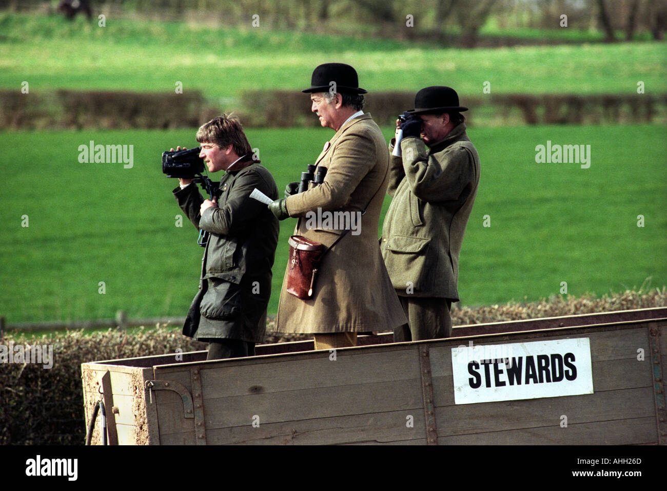 Horse racing stewards stand in a farm trailer to watch the racing at