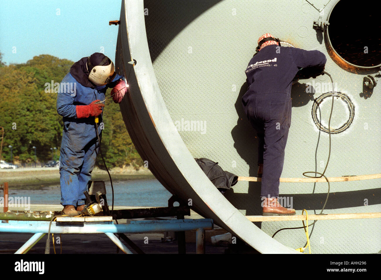 Welders working on large metal storage tank for the oil industry in Milford Haven Pembrokeshire West Wales UK Stock Photo