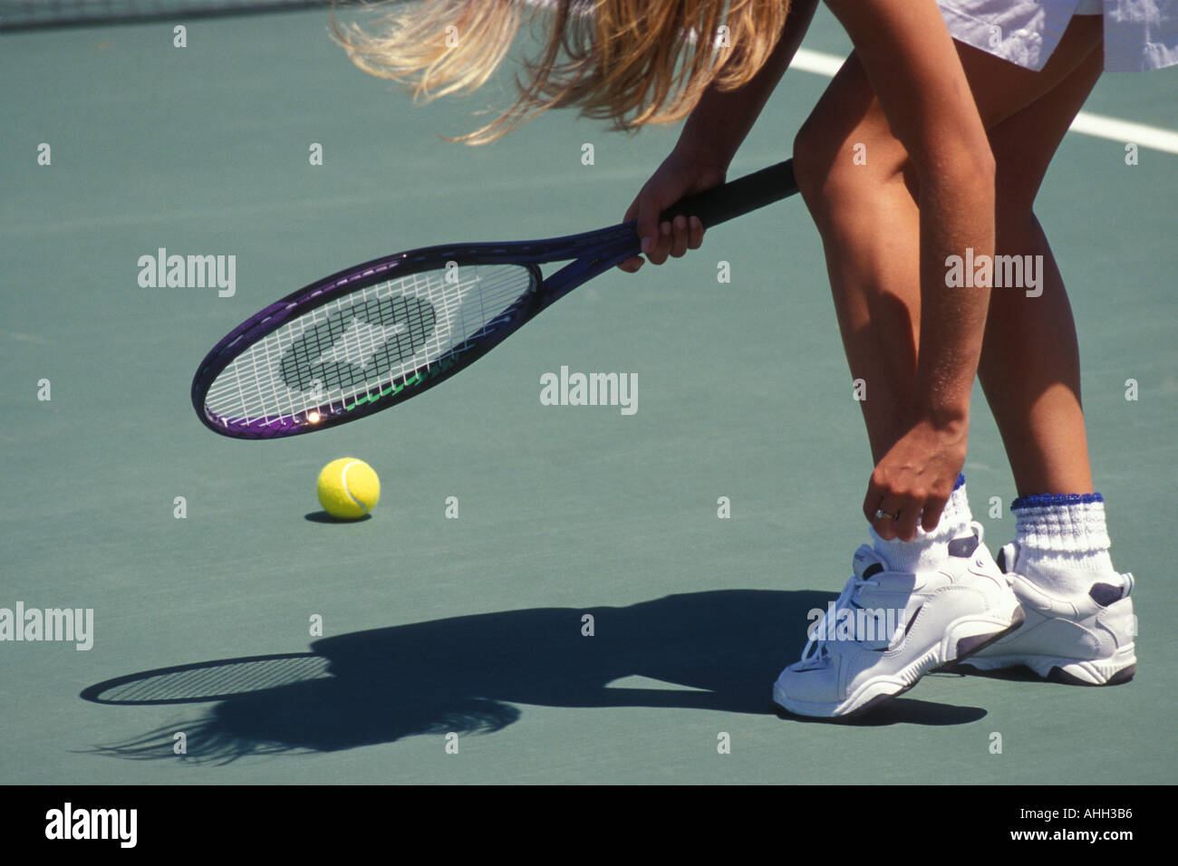 Girl adjusting Socks on Tennis Court Stock Photo