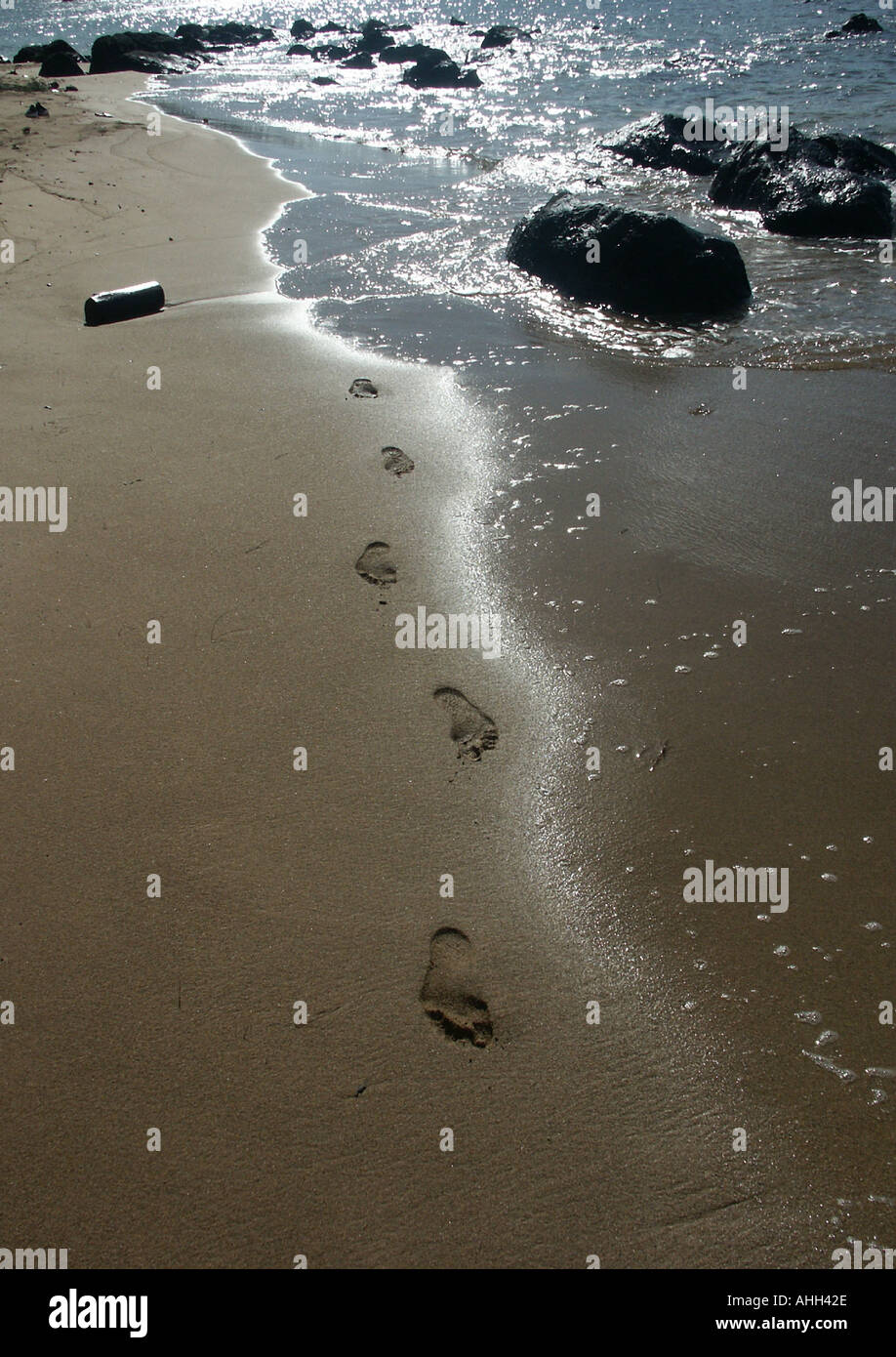 footprints and a tin can on the beach Stock Photo