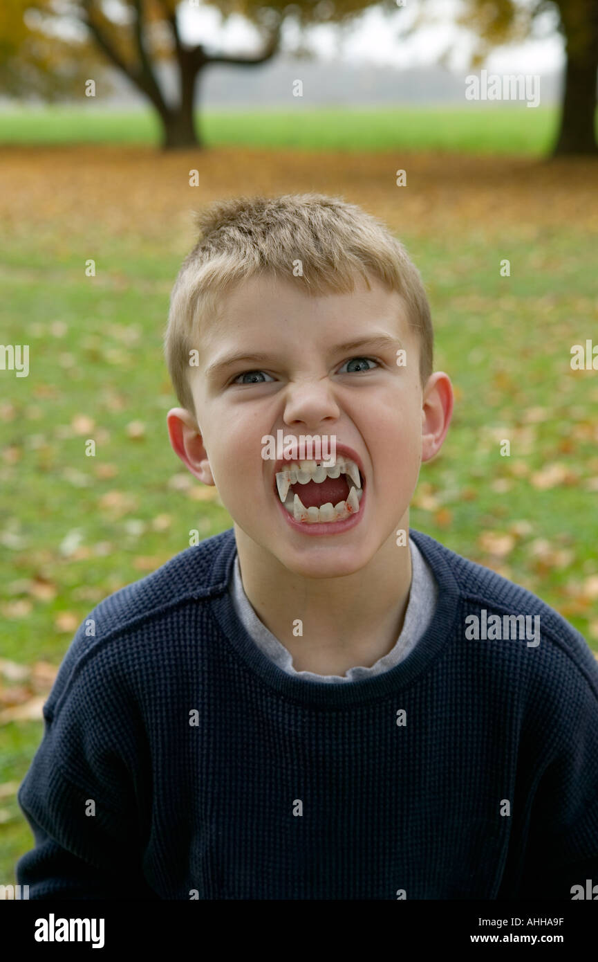 Boy eight years grimaces with vampire teeth on Halloween Stock Photo