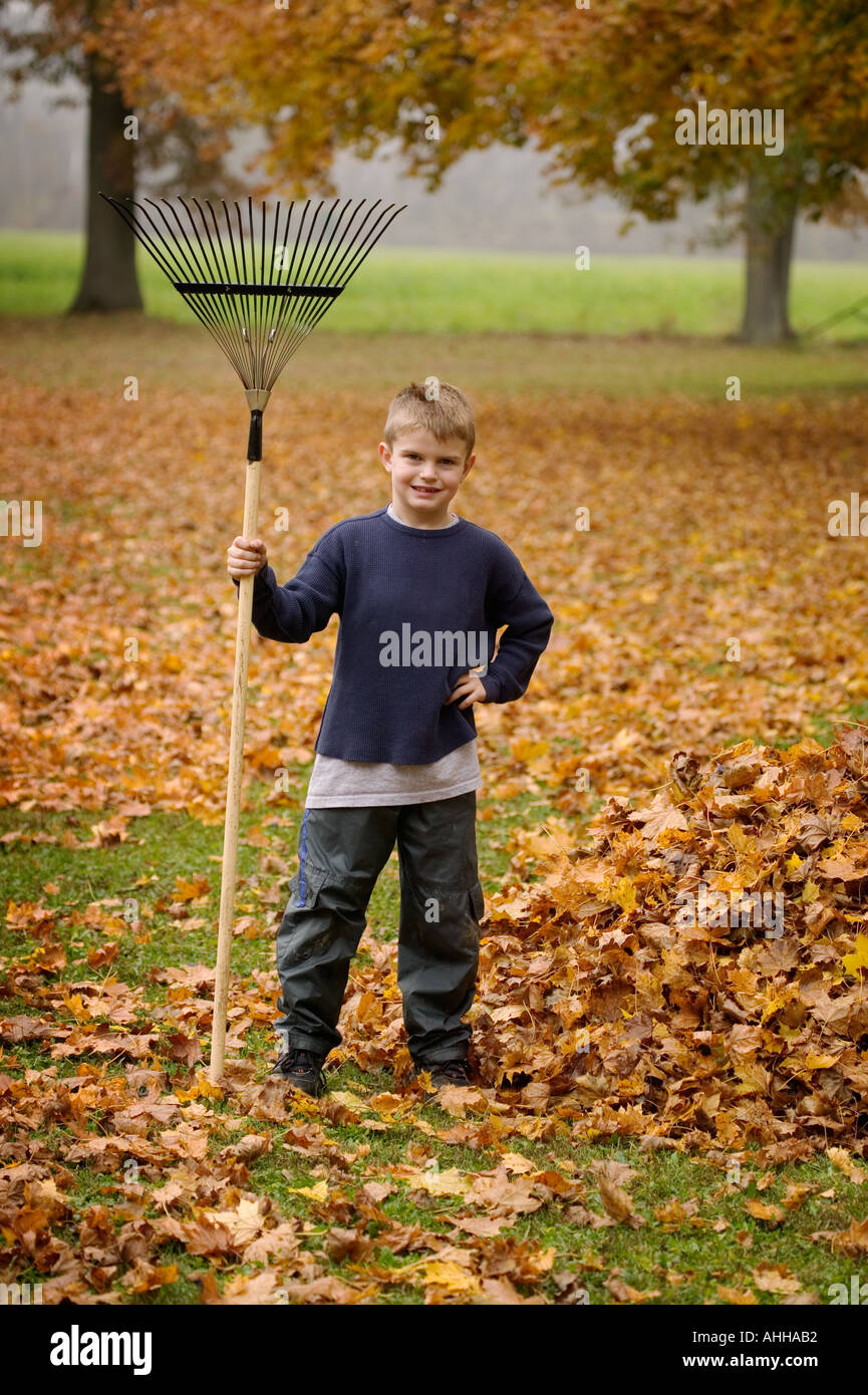 Boy 8 poses by a pile of leaves with a rake Stock Photo - Alamy