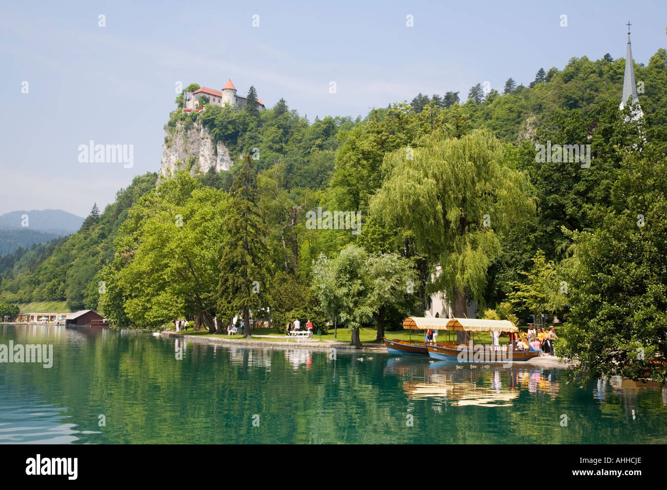 Lake Bled and Castle in summer with pletnja rowing boats moored on ...