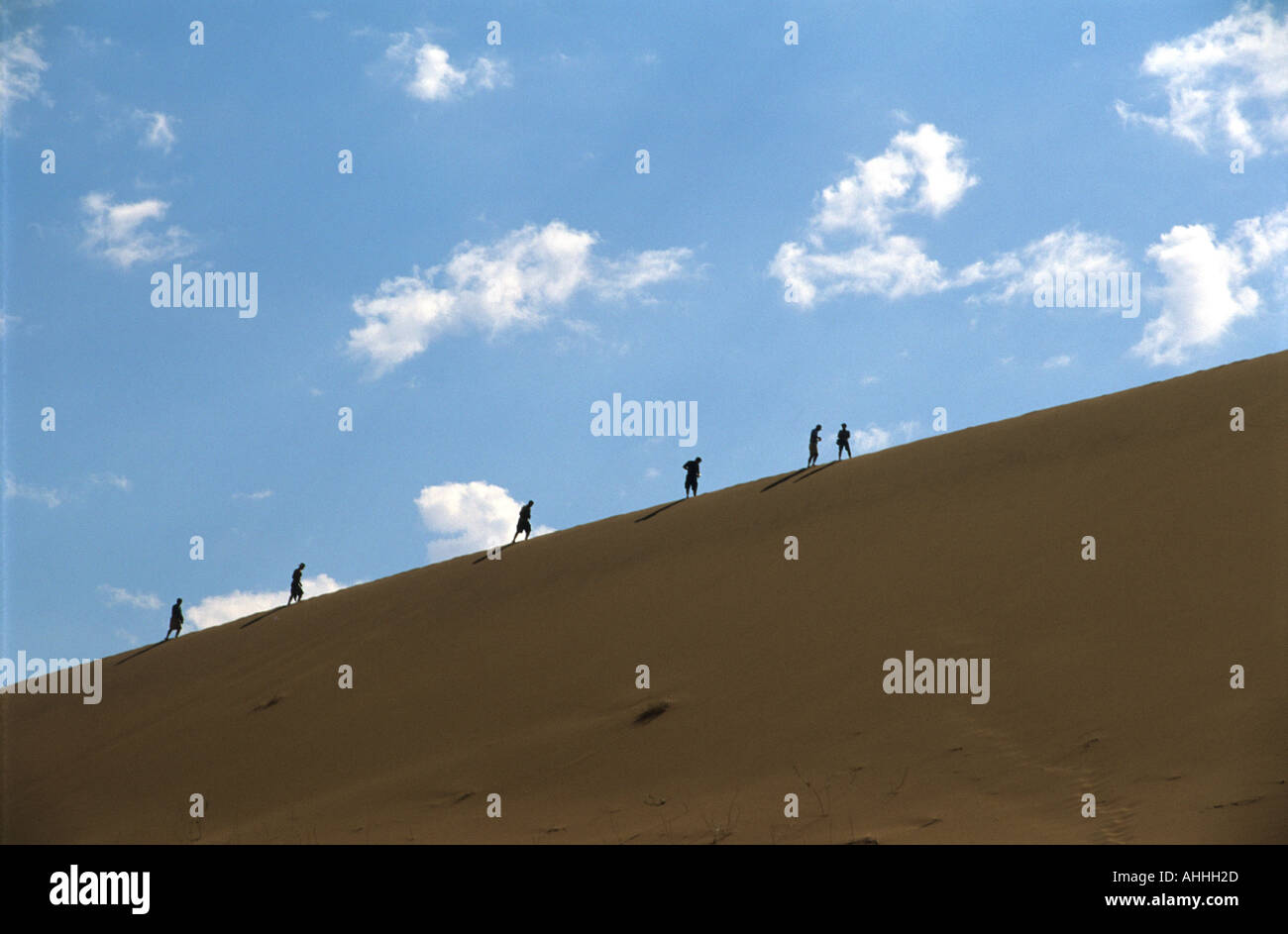 Walkers climbing dune in Namibian desert Stock Photo - Alamy