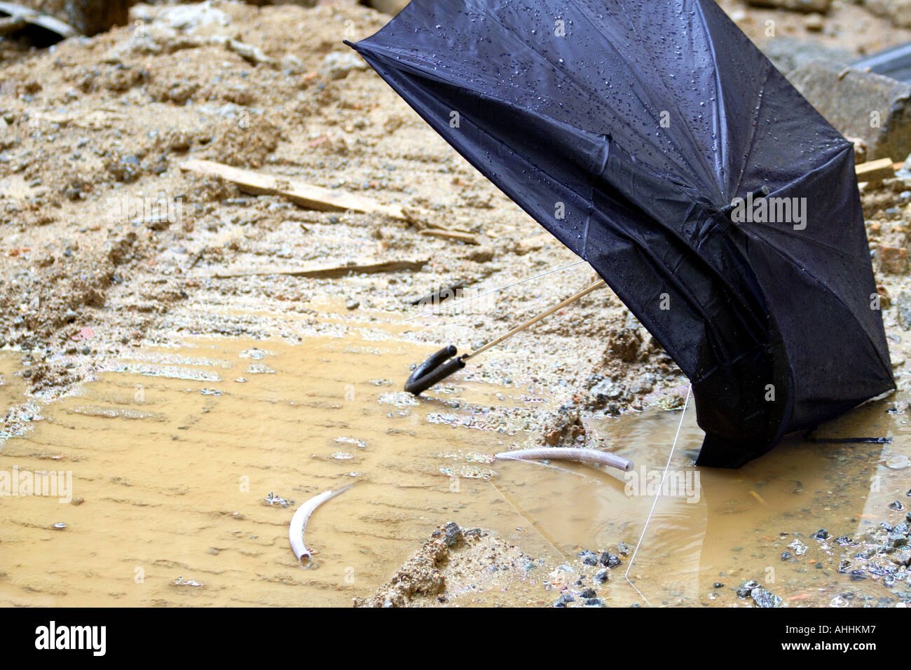 Broken Umbrella in the Rain, Laying in a Pool of Mud and Water Stock