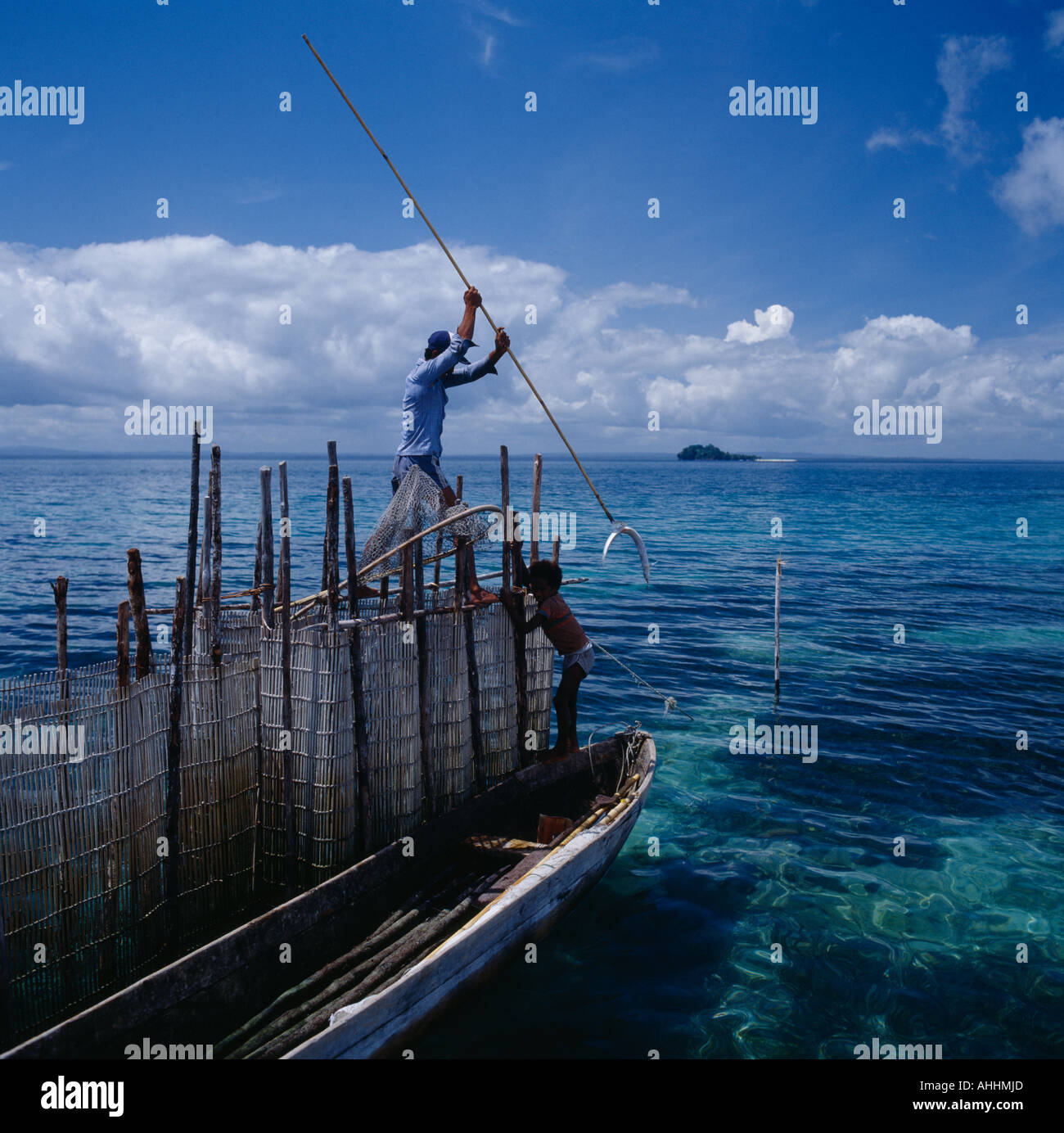 INDONESIA Southeast Asia Irian Jaya Sorong Fisherman on fishtrap by boat spearing fish in clear water with a long pole. Stock Photo