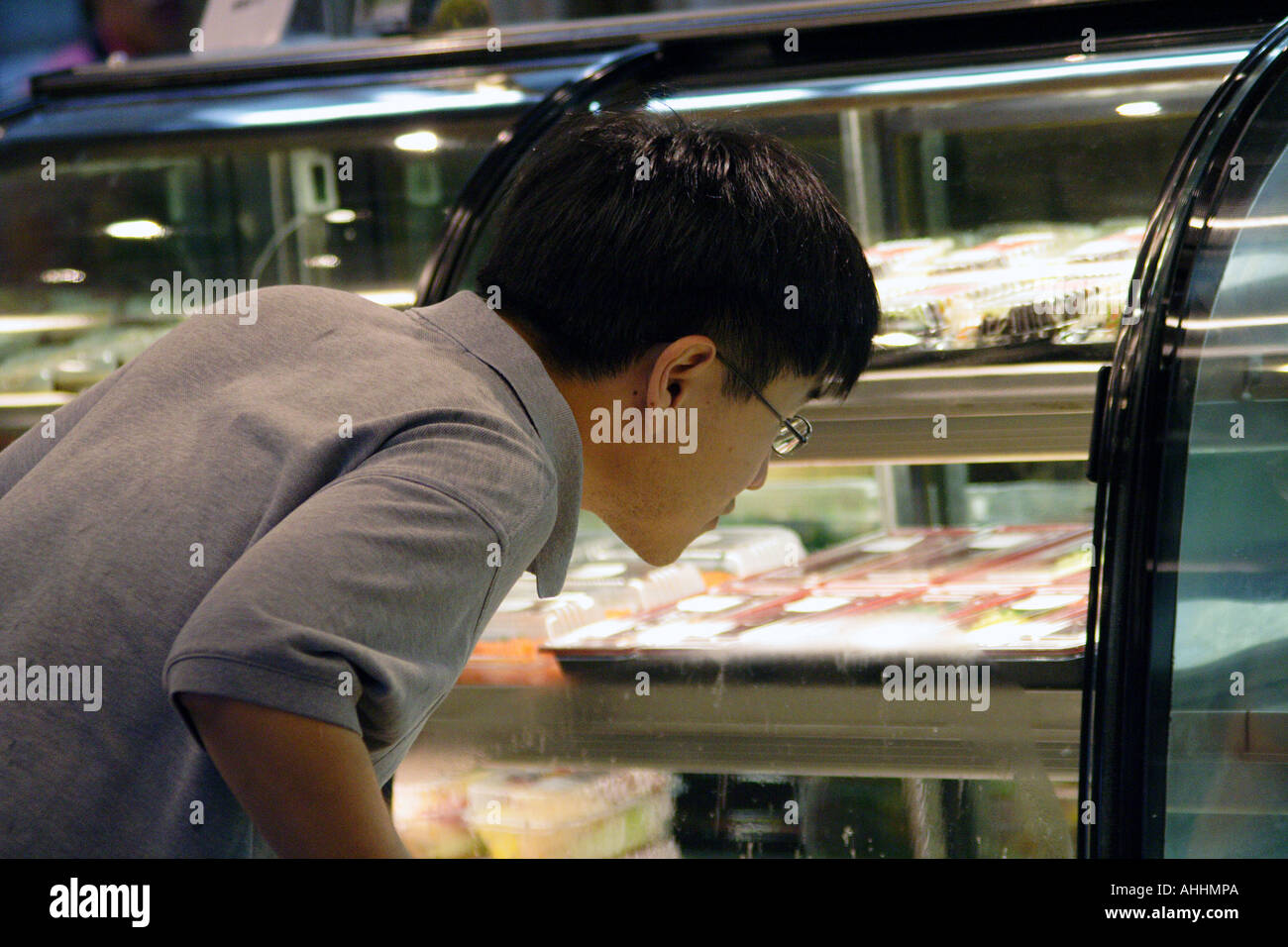 Young Asian Man Looking Closely into a Desert Display Case, Hong Kong Stock Photo